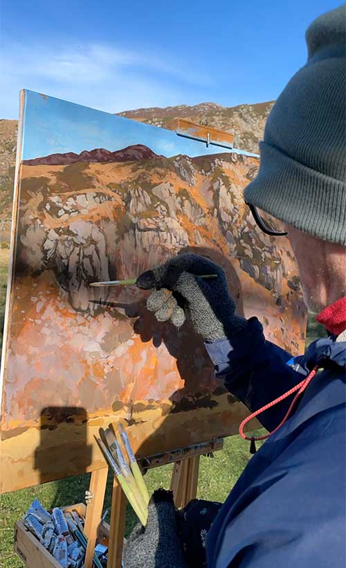 Kieran Guckian painting on location in Lough Dan Wicklow, the painting is in progress and is of a large rocky escarpment.