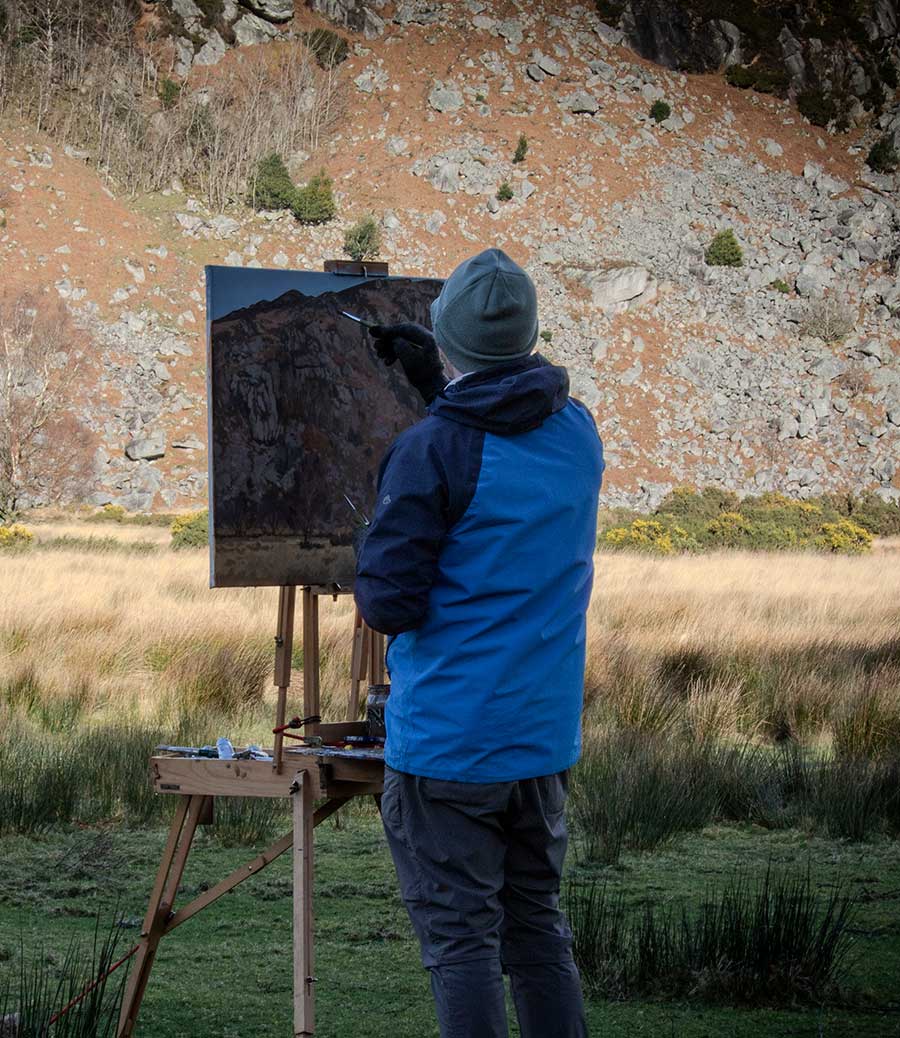 The artist Kieran Guckian at his easel painting on location in Lough Dan